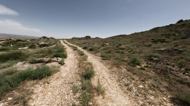 Off-road driving on winding dirt path through rocky terrain and grassland