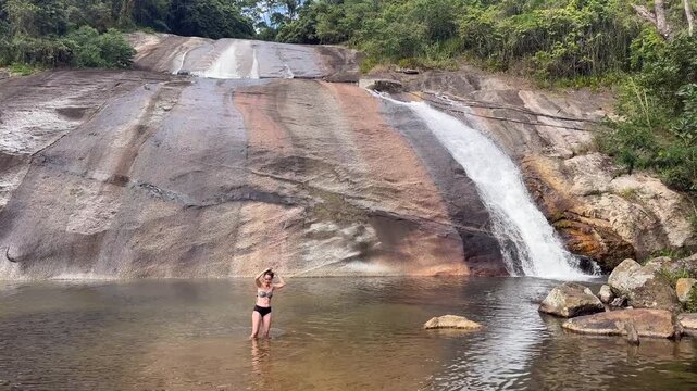 Woman Braving Cold Water in Natural Pool at Paqueta Waterfall, Ilhabela, Brazil