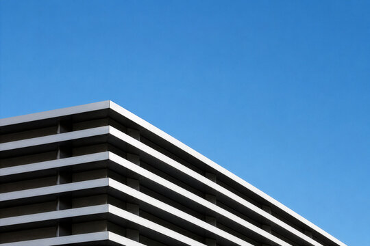Abstract geometric facade of modern corporate office building against clear blue sky. Minimalist architectural background with generous copy space for business or real estate concept.