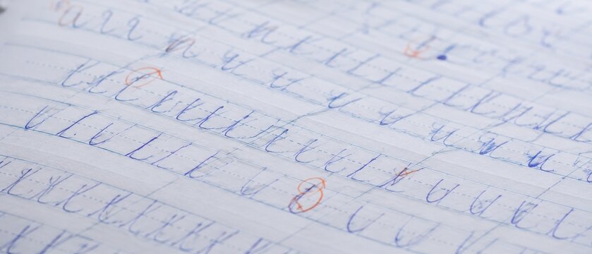 Close-up of handwritten cursive letters on lined paper, showing practice strokes