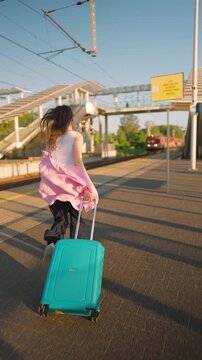 Caucasian woman pulling a suitcase and running, late for train.