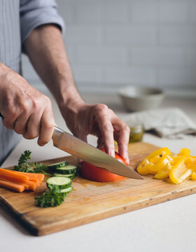 Hands slicing fresh vegetables on a wooden cutting board, healthy meal preparation and home cooking concept with natural ingredients