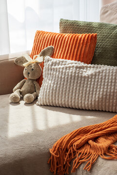 Cozy home interior scene with plush textured pillows and a soft stuffed rabbit toy