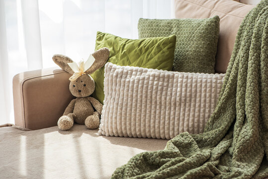 Cozy autumn scene with stuffed rabbit and textured pillows on a sofa indoors
