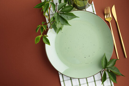 Elegant Table Setting With Green Plate And Gold Cutlery Decorated With Ivy Leaves For Thanksgiving Feast
