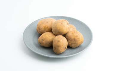 Fototapeta premium Fresh raw baby potatoes served on a grey ceramic plate isolated on white background