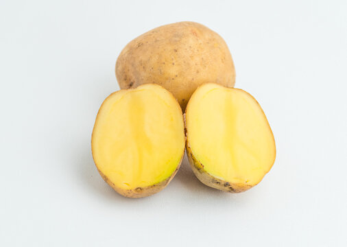 Fresh cut potato halves and whole potatoes isolated on a pure white background