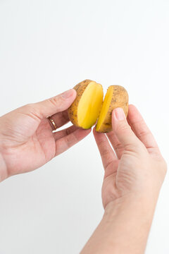 Female hands holding two halves of fresh cut raw potato isolated on white background
