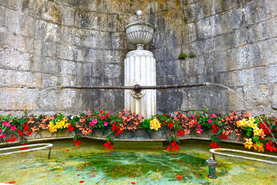 Baden im Kanton Aargau: Historischer Steinbrunnen mit bunten Blumen in einer steinernen Wandnische