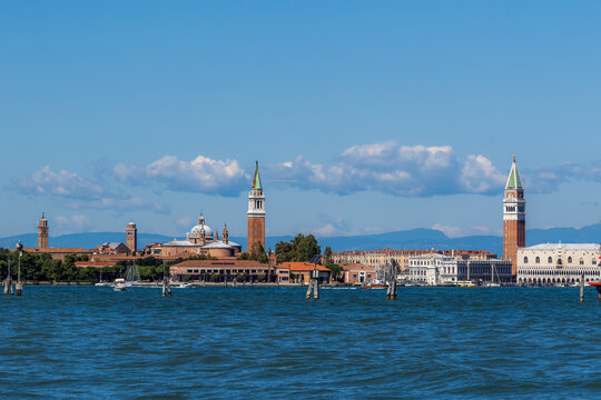 View of the historic skyline of Venice featuring St. Mark's Campanile and the Doge's Palace rising above the water under a clear blue sky in Venice, Italy.