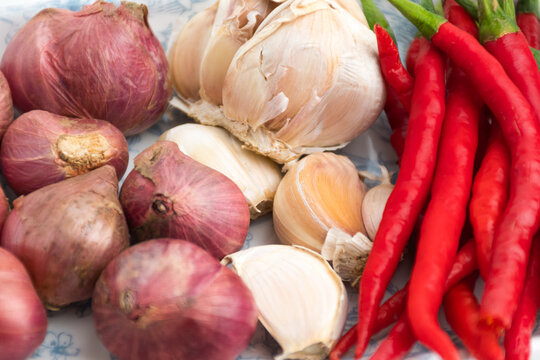Fresh red chilies shallots and garlic on ceramic plate isolated on white background