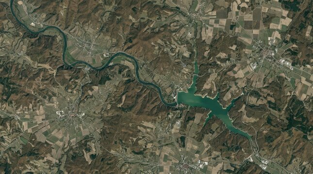 Stunning aerial satellite view of a winding river valley and a reservoir dam located in the rural European countryside
