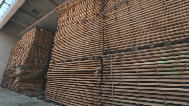 Air-drying and storage of wooden boards under a canopy at a furniture factory. Drying of stacked timber at a sawmill's lumber yard. Pile of timber, pile of lumber 
