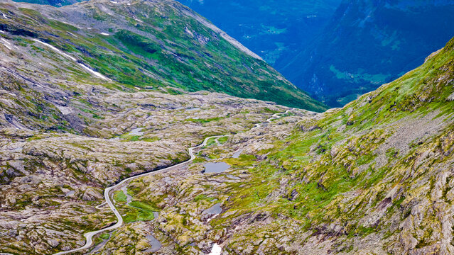 Aerial view of the winding road near Djupvatnet surrounded by rocky mountain terrain and small alpine pools in Stranda Municipality, More og Romsdal, Norway.