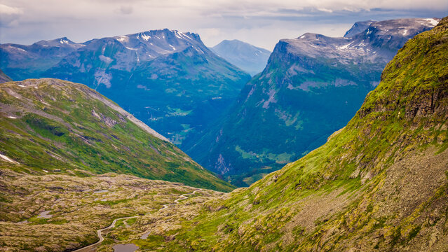 Aerial view of Djupvatnet lake surrounded by rugged mountains, winding roads, and lush green slopes in Stranda Municipality, More og Romsdal, Norway.
