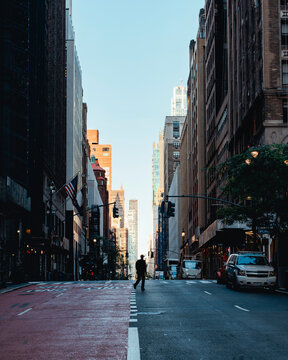 Pedestrian Crossing Quiet Manhattan Street Between Tall Buildings in New York City