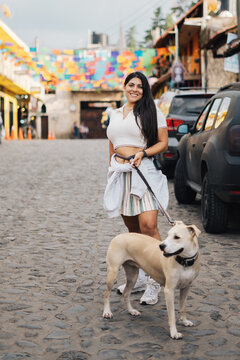Young woman with her dog enjoying a walk on a cobblestone street in huasca de ocampo