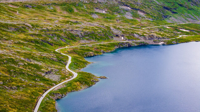 Aerial view of Djupvatnet lake with a winding road tracing the shoreline through the rugged mountainous landscape of Stranda Municipality, More og Romsdal, Norway.