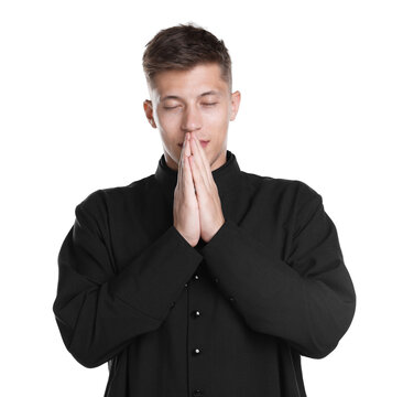 Young priest in cassock with clasped hands praying on white background