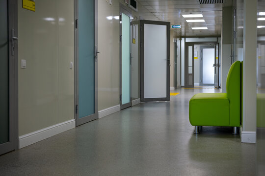 Empty modern hospital corridor with green chair and doors