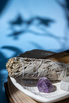 sage smudging ritual with crystals on wooden plate for spiritual cleansing and relaxation