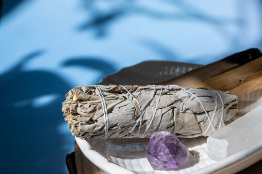 sage bundle and amethyst crystal casting shadows on a sunny day. concept of spiritual cleansing