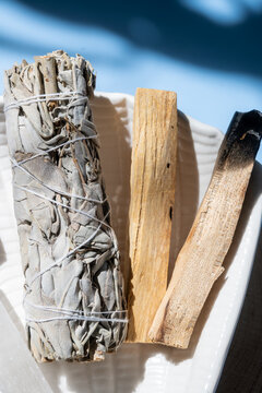 sage smudge stick and palo santo on a ceramic dish for spiritual cleansing