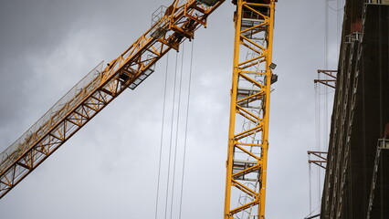 Tower crane at a modern construction site showing industrial equipment, urban development, engineering progress and building industry growth against cloudy sky © belavinstock