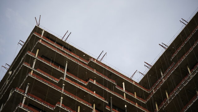 Concrete frame of unfinished high rise building under construction representing urban expansion, modern architecture, engineering progress and real estate development