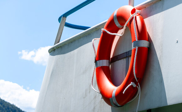 Bright orange lifebuoy on board a boat, representing water transport and the boating setting in a clean maritime environment.