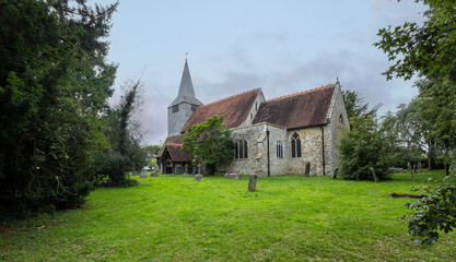 Fototapeta premium High Halden, Kent, united kingdom, 21, August, 2022 Historic Stone Parish Church With Steeple and Graveyard in English Countryside Under Overcast Sky