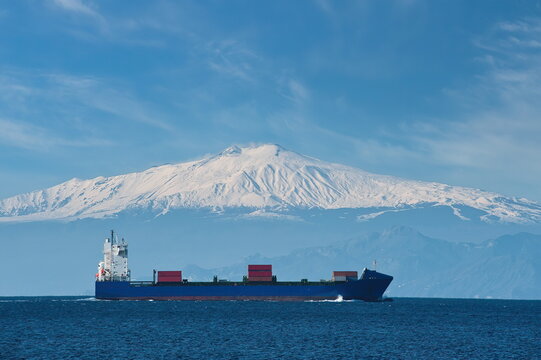 Nave portacontainer in transito nello Stretto di Messina a Lazzaro con il vulcano Etna innevato