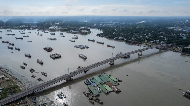 Aerial view of numerous cargo ships anchored in the Karnaphuli River near a bridge in the industrial port area of Chittagong, Chittagong Division, Bangladesh.