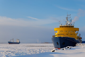 Powerful modern icebreaker ship locked in ice of frozen river under blue sky with copy space. Arctic maritime transport and logistics. © Konstantin