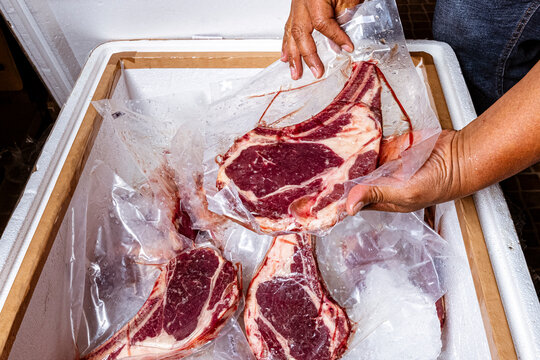 High-quality fresh beef steak cuts like Tomahawk, T-bone and Ribeye uncooked on wooden platters, with fresh ingredients