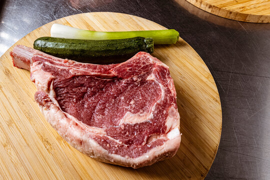 High-quality fresh beef steak cuts like Tomahawk, T-bone and Ribeye uncooked on wooden platters, with fresh ingredients