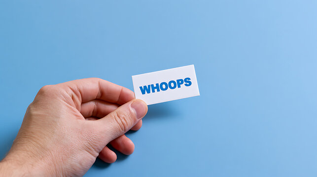 A person's hand holding a white card with the word "WHOOPS" in blue text, against a light blue background, conveying a sense of error or mistake