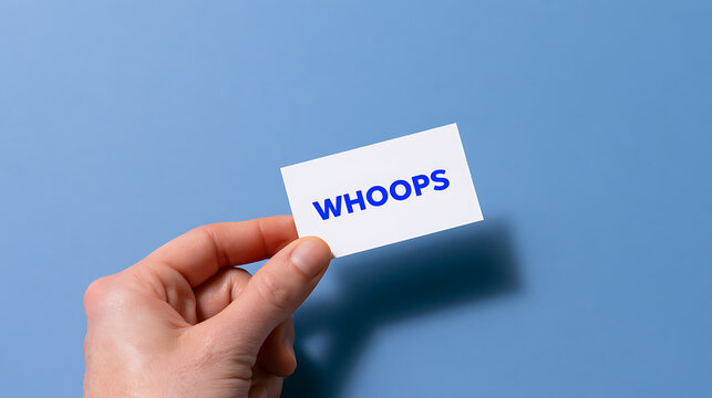 Human hand holds a white card with blue "WHOOPS" text, conveying an error, mistake, or apology on a blue background, concept of oops