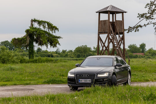 Black Audi Sedan Parked On Country Road Near Wooden Watchtower In Green Countryside Landscape