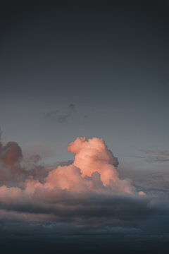 View of a large, pink-lit cumulus cloud formation against a dark, moody evening sky over Vormsi, Laane County, Estonia.