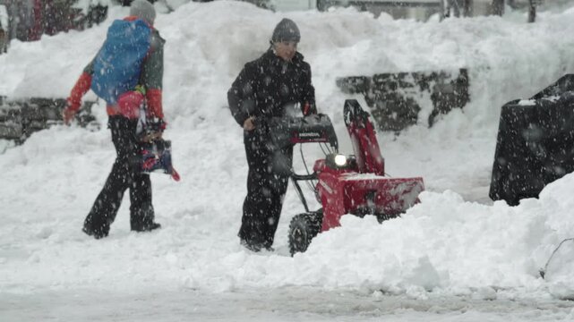 Worker clearing heavy snow with snowblower machine