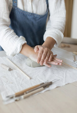 Potter artist forming clay in a focused and creative ceramic studio side view with white and gray tones and wooden tools, artistic hobby and crafting visual resource for web banners and posters.