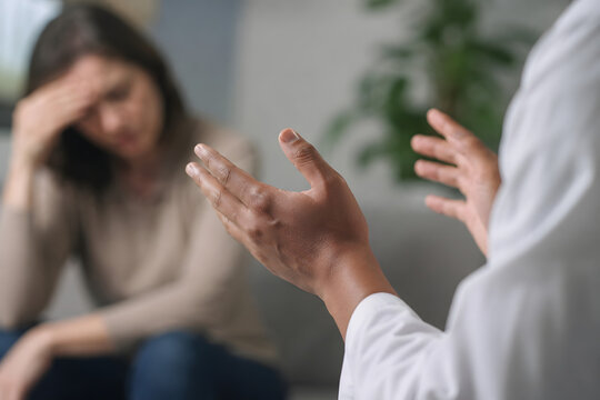 Healthcare professional using open hands to de-escalate a difficult patient conversation, highlighting calm communication, empathy, patient safety and conflict prevention.
