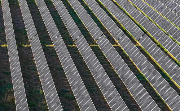 Aerial view of long parallel rows of photovoltaic panels mounted on single-axis solar tracking systems in a large-scale renewable energy farm in Le Pouzin, Auvergne-Rhone-Alpes, France.