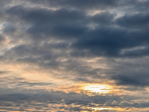Golden Sunset Light Breaking Through Dark Layered Clouds in a Dramatic Evening Sky