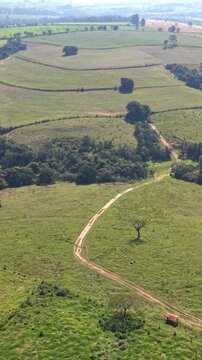 High angle aerial view of vast agricultural fields, pasture, and crop land captured by drone during a clear sunny day.
