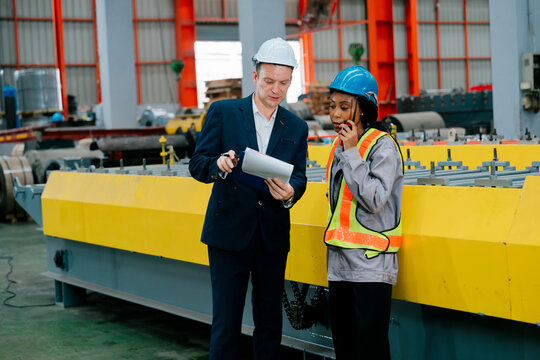 Professional engineer inspector team evaluates metal sheet manufacturing industry operations with happy confident smile in factory
