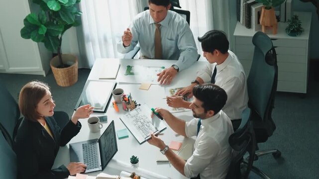 Top down view of skilled engineer team compare between blueprint and house plan. Aerial view of group of architect or designer discussing and point note to brainstorm about blueprint. Alimentation.