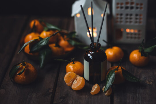 Sweet citrus home reed diffuser. Creating coziness during holiday season. Traditional Christmas or new year scent. Tangerine, orange perfume, house deodorant . Festive atmosphere, atmospheric lights