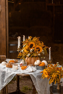 Cozy autumn composition near old wooden country house. Table setting for family thanksgiving dinner with homemade apple pie, bouquet of sunflowers, pumpkins. Elegant rustic cottage core home decor